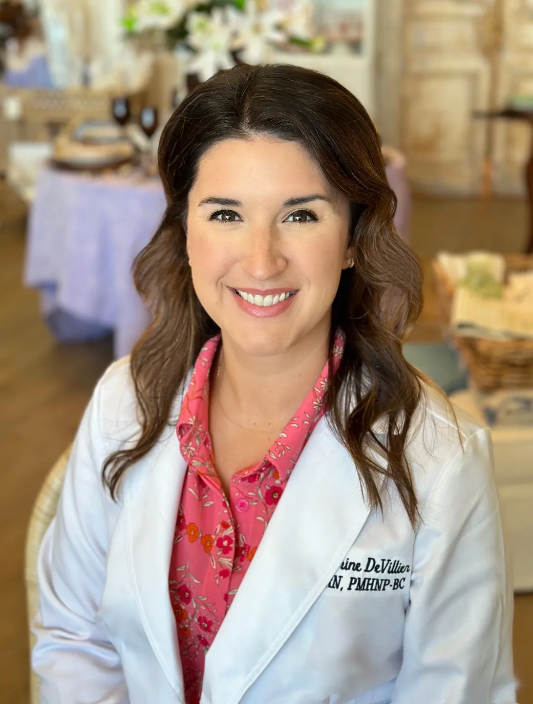 A woman in white lab coat standing next to table.