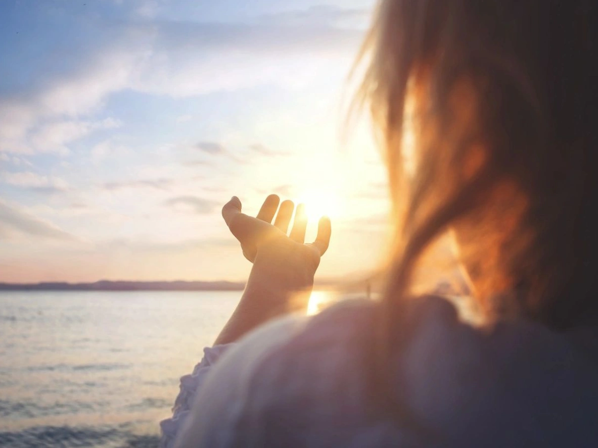 A woman holding her hand up to the sun.