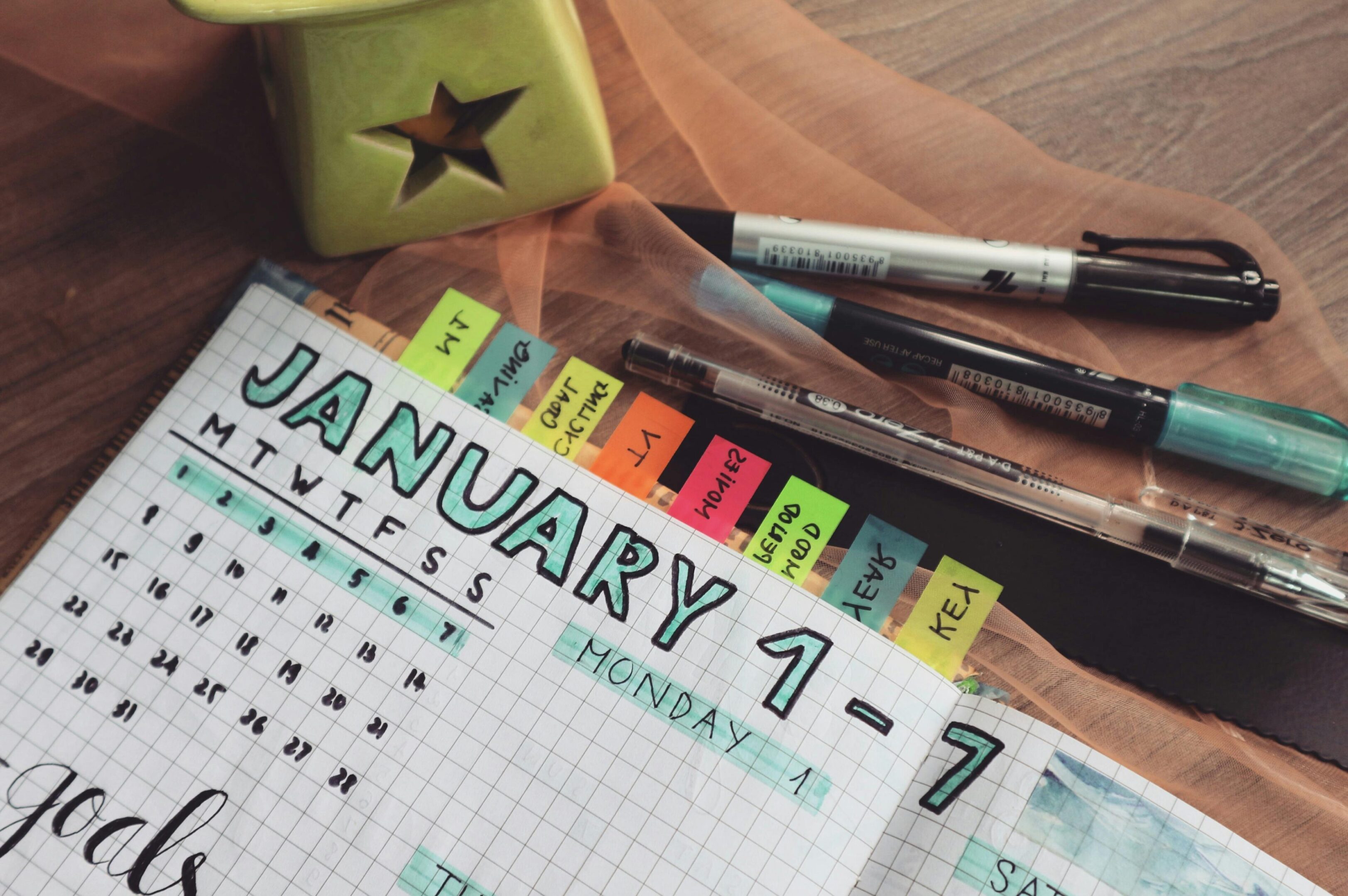 A desk with some markers and an open calendar